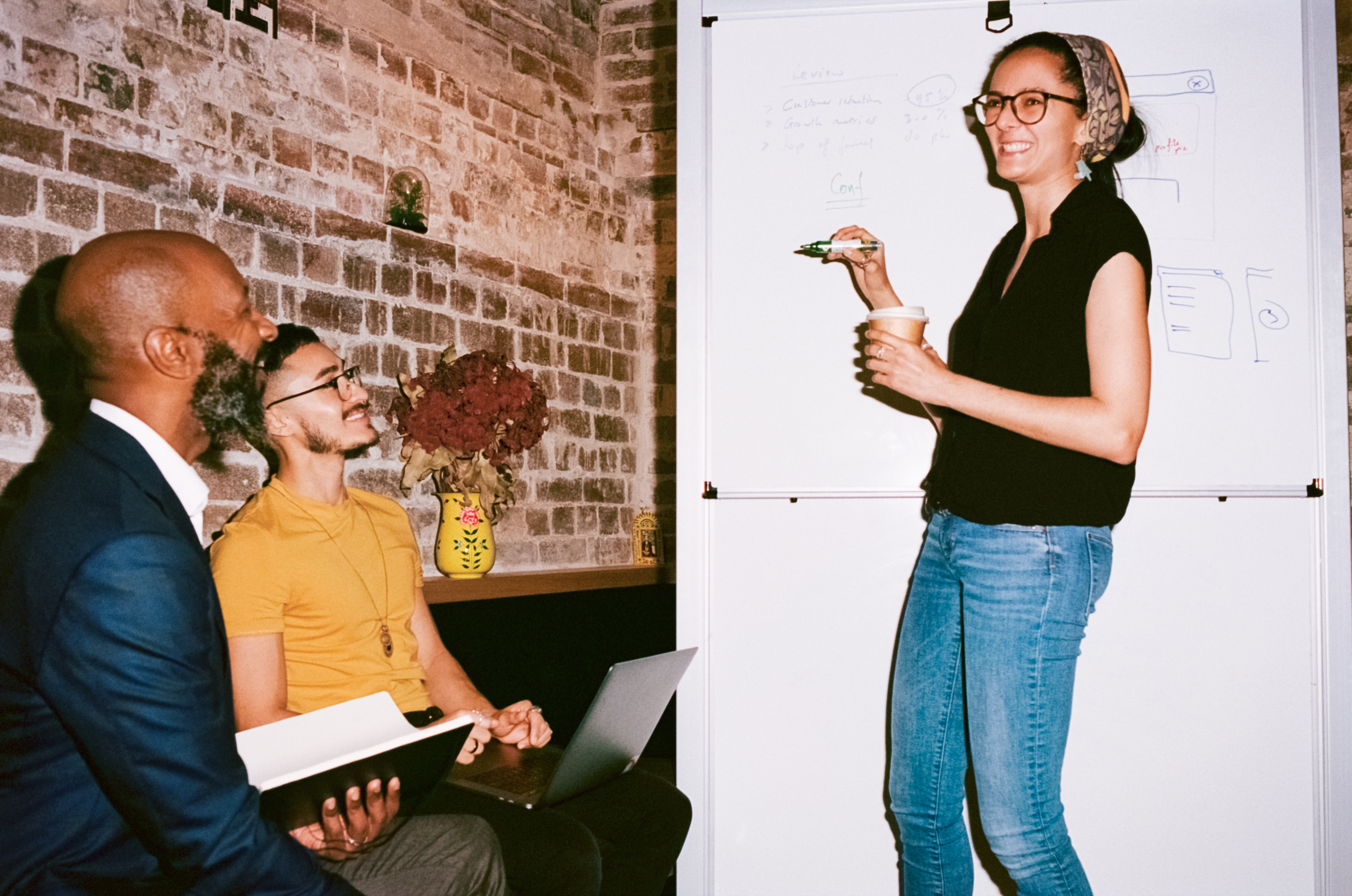Three colleagues around a whiteboard, mid-discussion.
